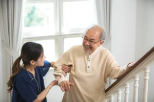 a NDIS provider in Wollongong helping an older man in stairs.